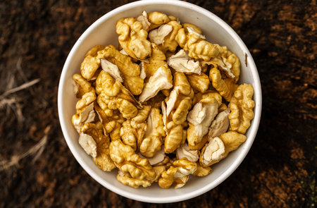 Walnuts in a white bowl on wooden background. Top view.