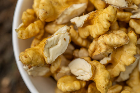 Close up of peeled walnuts in a white bowl on wooden background