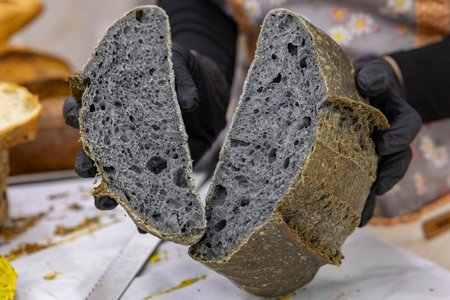 Sliced black bread in the hands of a female baker.