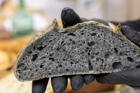 Close up of a black bread in the hands of a baker.の写真素材