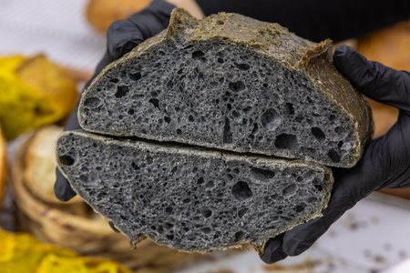 Closeup of a black bread in the hands of a woman.の写真素材