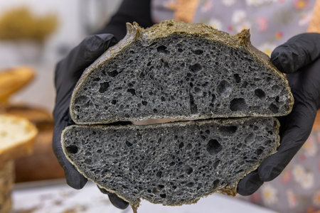 Freshly baked black bread in the hands of a female pastry chefの写真素材