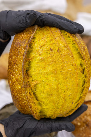 Close-up of a freshly baked loaf of bread in the hands of a bakery worker
