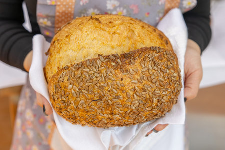 Bread with sunflower seeds in the hands of a woman.