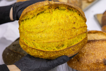 Freshly baked bread in the hands of a woman in black glovesの写真素材