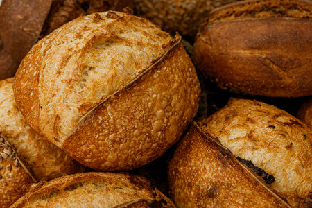 Variety of baked breads and buns on wooden background.