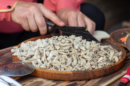 Mushrooms on a wooden plate with a knife in the hands of a cookの写真素材