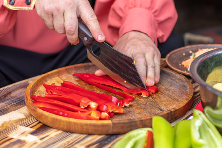 Chef cutting red bell pepper on a wooden board, closeupの写真素材