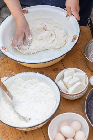 Woman's hands kneading dough in a bowl with flour.