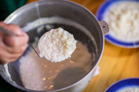 Cooking rice porridge in a pot on a wooden table.