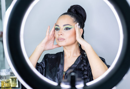 Portrait of a beautiful young woman applying make-up in front of a mirror