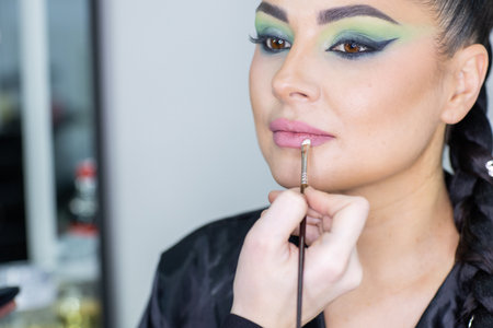 Makeup artist applying make-up on the face of a beautiful womanの写真素材