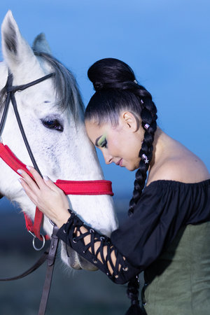 View of a girl in classic dress next to a white horse.の写真素材