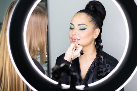 Young beautiful woman applying make-up in front of a mirror.の写真素材