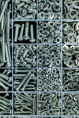 Metal bolts and nuts in a box close-up. Industrial background.