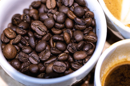 Coffee beans and cup of coffee on wooden table background.