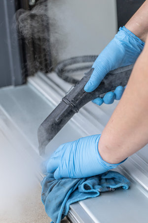 Hand of a woman wearing blue gloves cleaning with a cloth