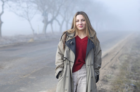 Portrait of a beautiful young woman in the fog on the road