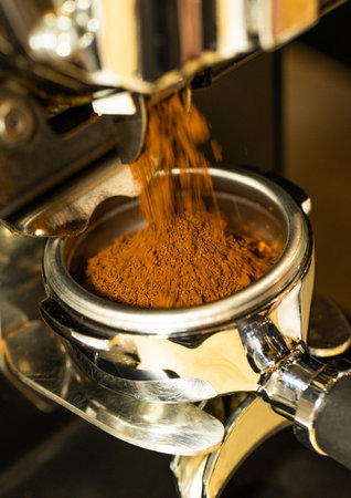 Close up of a coffee machine pouring ground coffee into a cup.