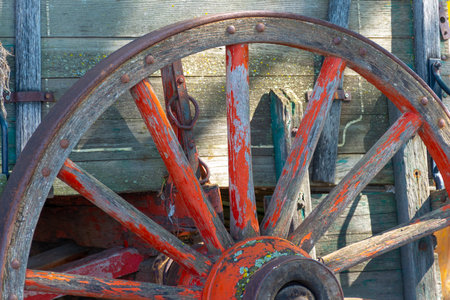 Old wooden wagon wheel on a sunny summer day close-up.