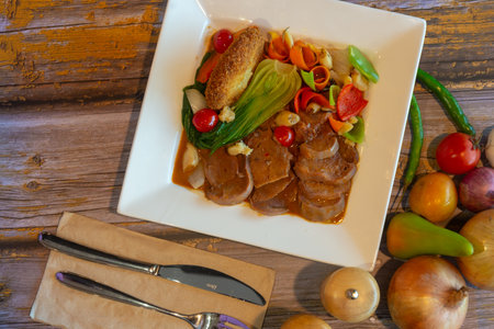Fried duck fillet with vegetables on white plate on wooden tableの写真素材
