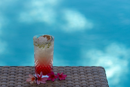 Alcoholic cocktail drink on a swimming pool background. Cocktail in a glass