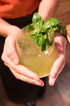 Close-up of woman hands holding a glass of fresh basil cocktailの写真素材