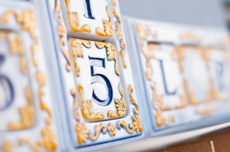 enameled number five with yellow decoration and blue writing on white backgroundの写真素材