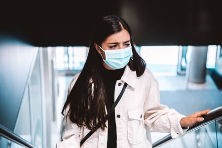 Corona - Covid-19 conceptual image of a woman wearing face mask while shopping and holding railingの写真素材