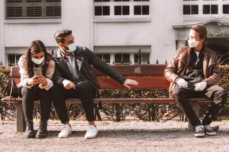 corona covid-19 social distancing concept picture with three people wearing face masks - stay away