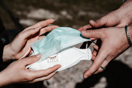 Woman gives a man two face masks for protection against pathogens - covid-19 concept picture