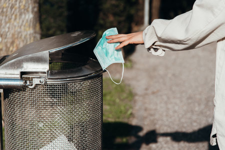 Used face mask is thrown in the trash can outside after the pandemicの写真素材