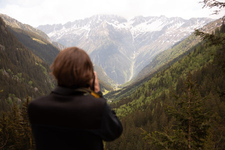 Man photographing beautiful mountainous landscape with valley and forests