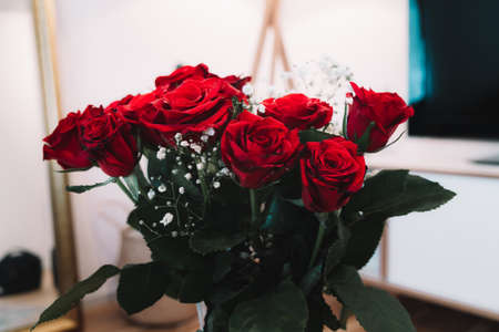 Red roses with white flowers in a vase - home decorationの写真素材