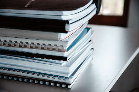 Stack of reports lies on a desk ready for reviewの写真素材