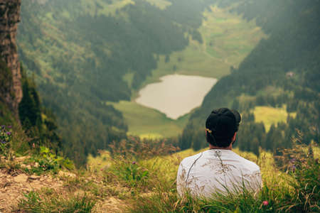 A man sits on the top of a mountain after a nice hike and admires the natureの写真素材