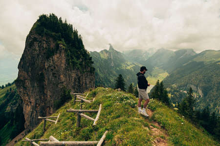 A man stands on the top of a mountain after a nice hike and admires the natureの写真素材