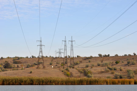 high-voltage pole stands in a field in autumn
