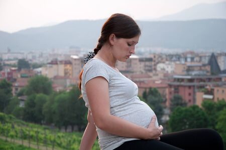 a pregnant woman against the backdrop of the city in the eveningの写真素材