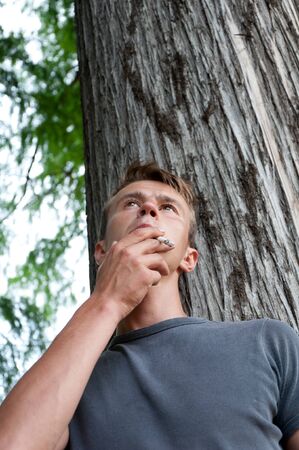 young man smoking in the parkの写真素材