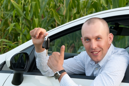 smiling man sitting in the car and showing keysの写真素材