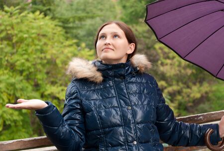 girl with an umbrella in the park watching the rain comesの写真素材