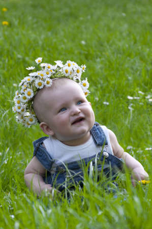 little boy in a wreath sitting on grassの写真素材