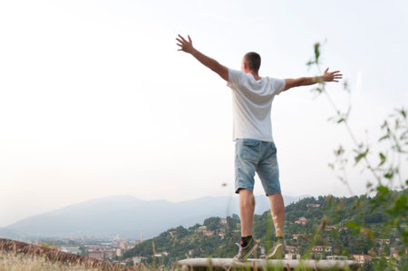 young man arms outstretched to the side at city viewsの写真素材