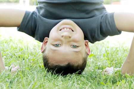 happy boy upside down on the grass in the parkの写真素材