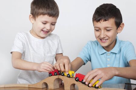 Two boys having fun with a wooden trainの写真素材