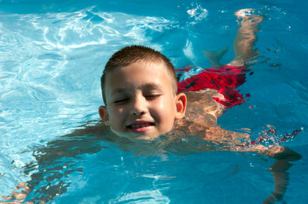boy swims in the pool enjoying a vacationの写真素材