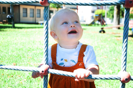 little blonde girl smiling at the playground in summerの写真素材