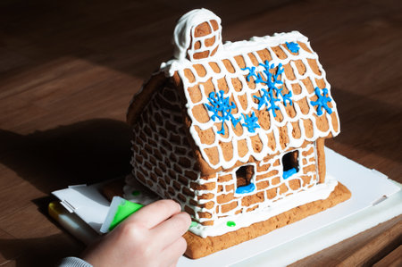 decorating a gingerbread house with icing for Christmasの写真素材
