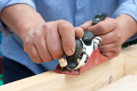leveling wood with a plane, close-up of carpenter's hands